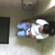 A hidden camera mounted on the ceiling captures a seemingly unsuspecting woman peeing on a toilet, then wiping. No audio.